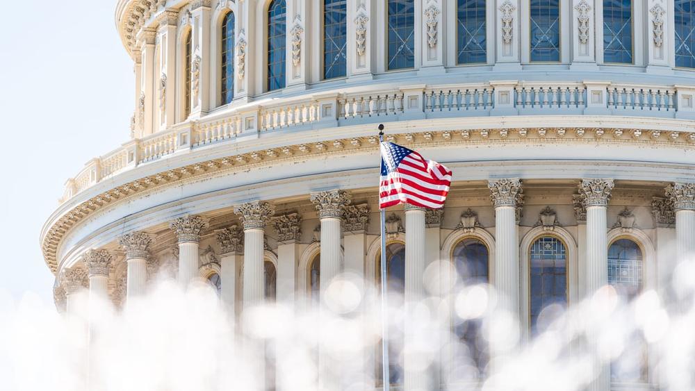 US Congress dome closeup with background of water fountain splashing, American flag waving in Washington DC, USA closeup on Capital capitol hill, columns, pillars