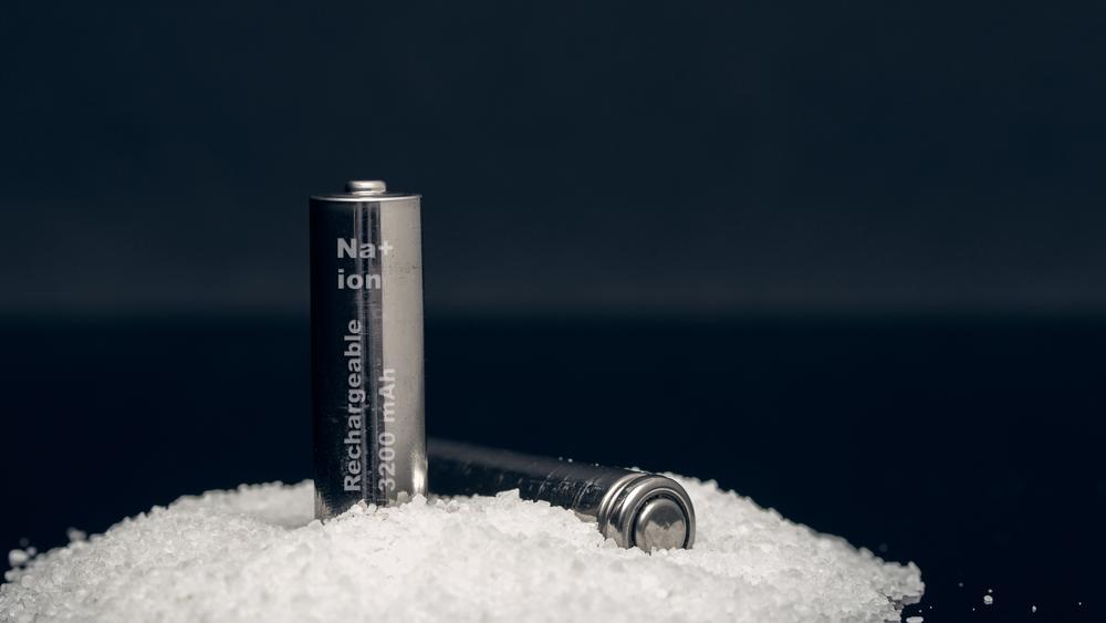 Two sodium ion batteries in pile of salt on black background