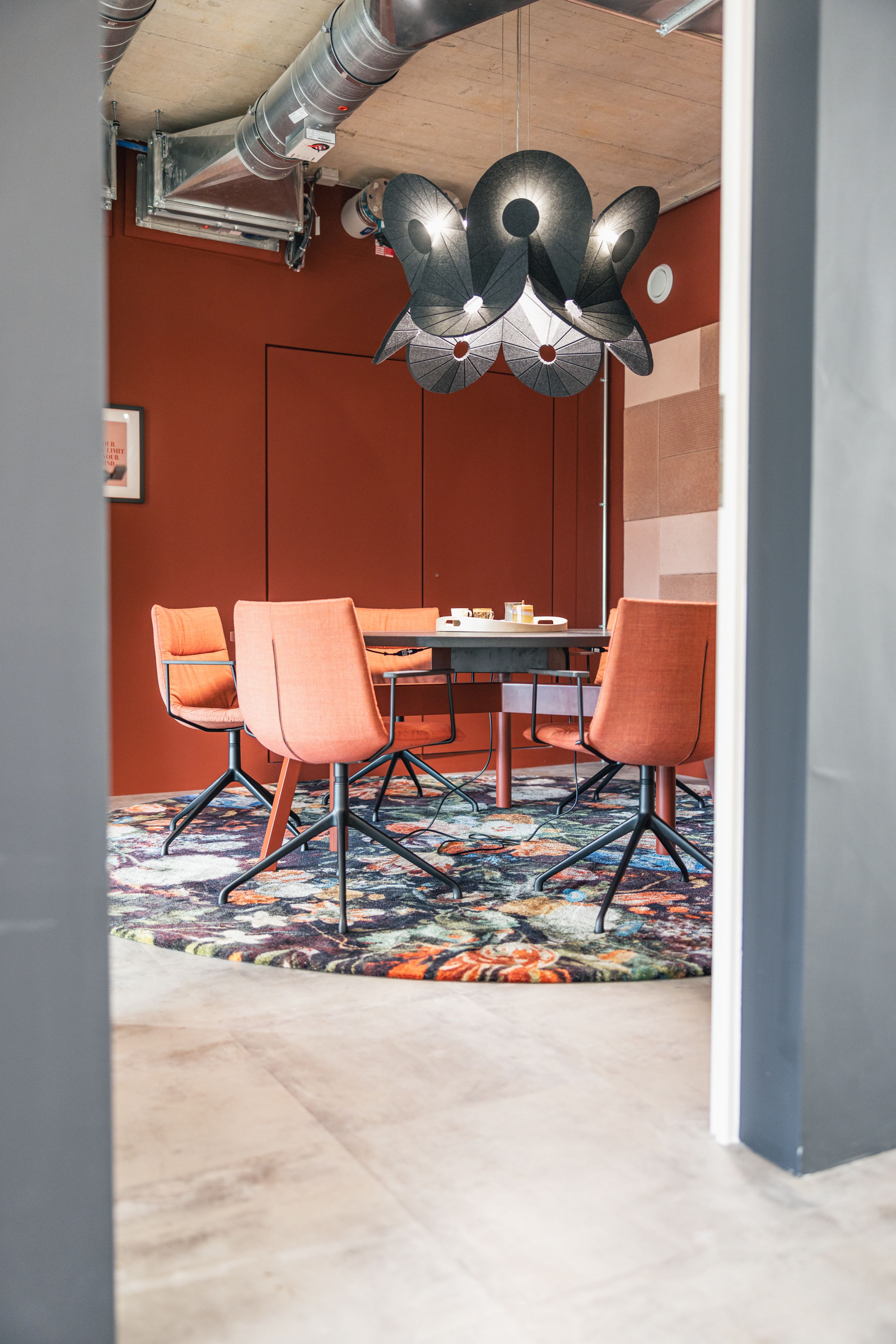 Sitzungszimmer mit roten Stühle und schwarzem Tisch. Im Zimmer selbst sitzt niemand.