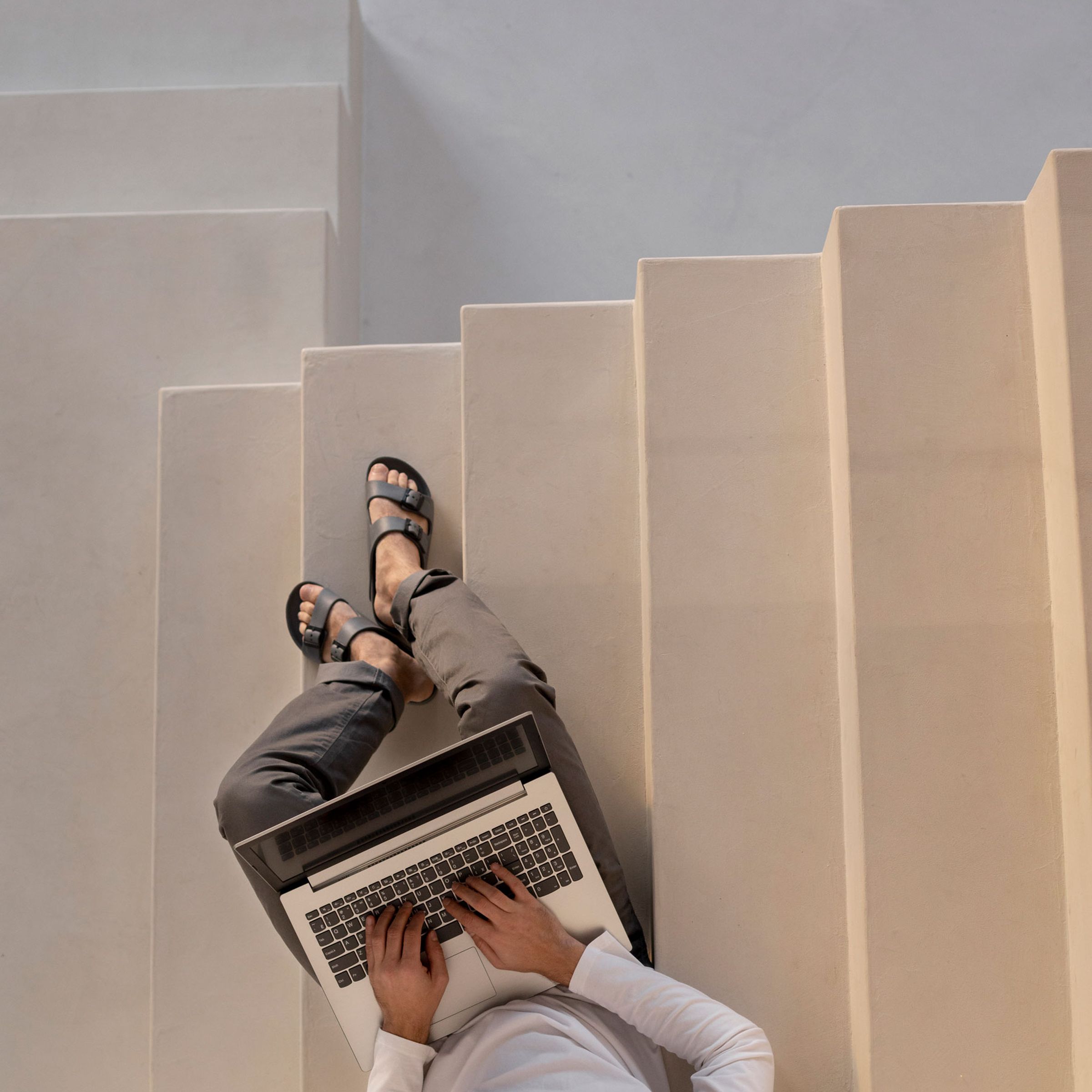 Mann mit Laptop auf Treppe sitzend.