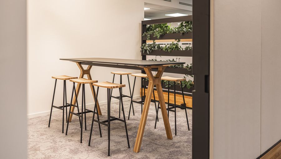 Meeting-Spot mit Holz-Hochtisch und Barhockern. Minimalistisch und kommunikativ.