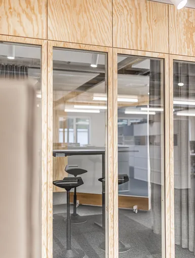 Abgedunkelter Raum mit Holzsitzbank und kleinen Hockern.