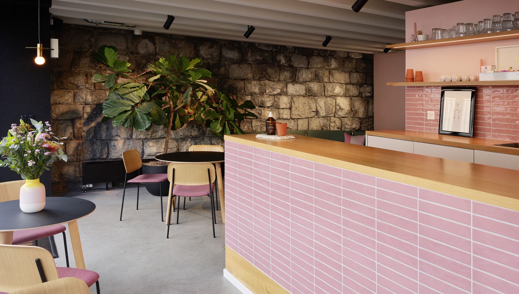 Nahaufnahme eine Theke mit pinken Kacheln. Daneben Coffee-Table mit Stühlen.