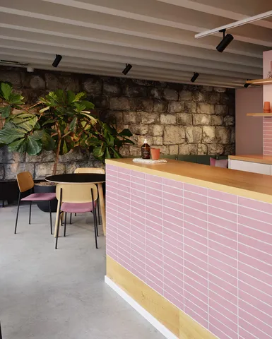 Nahaufnahme eine Theke mit pinken Kacheln. Daneben Coffee-Table mit Stühlen.