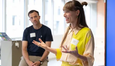 Eine Person spricht. Die andere Person schaut sie von der Seite an.