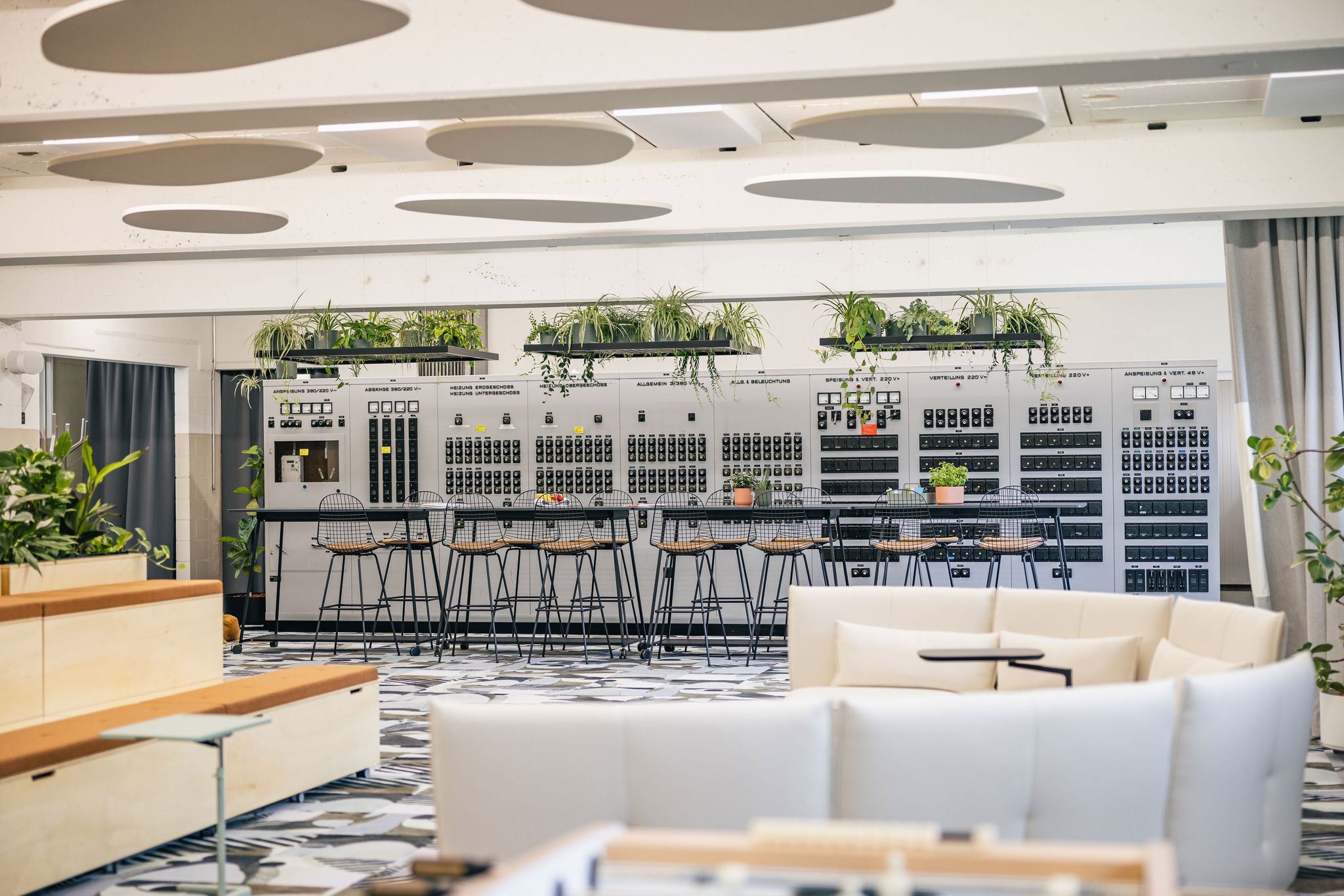 Offener Meetingbereich mit Pflanzen, Holzpodesten und großem Bildschirm.