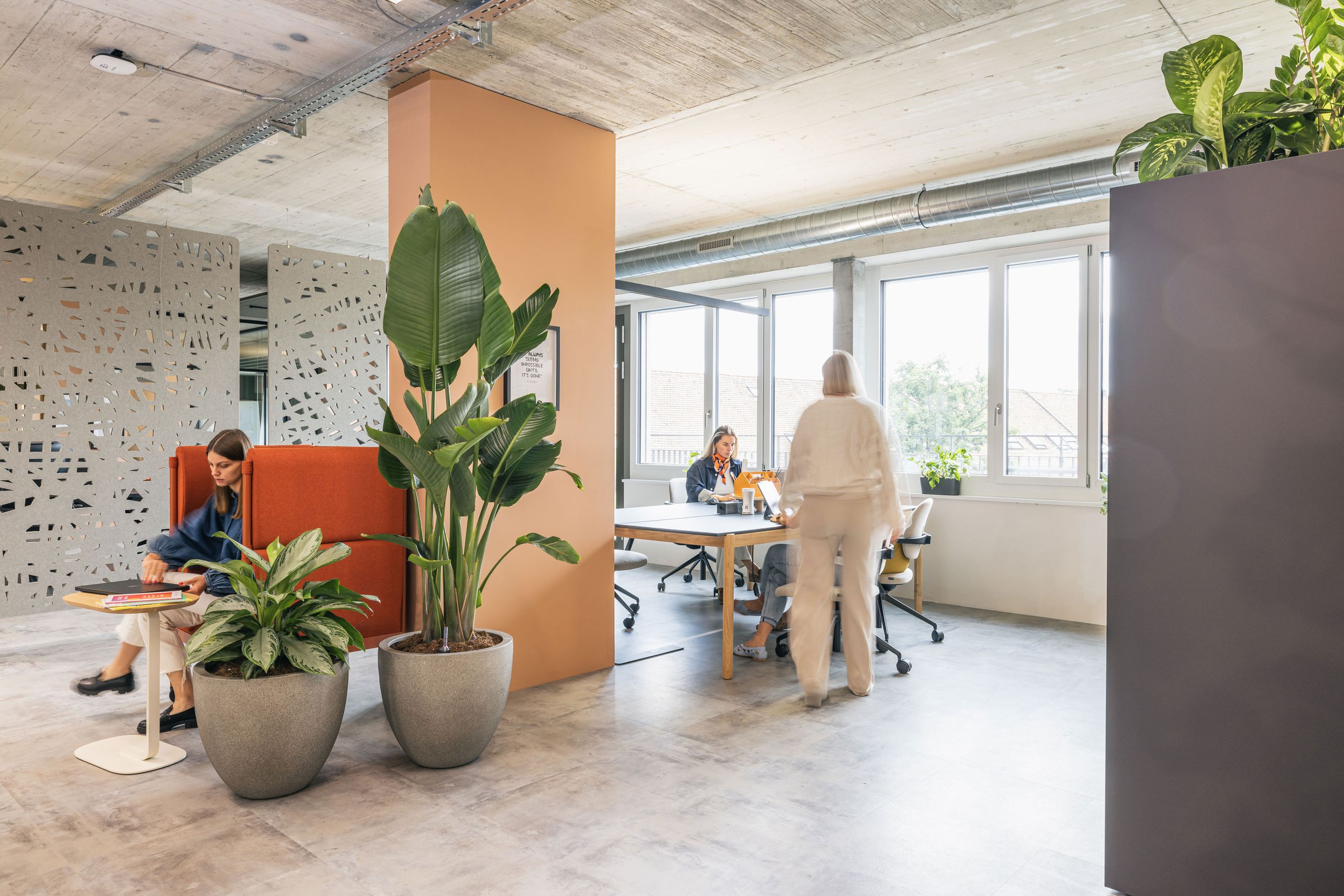 Offener Teamarbeitsbereich mit Lounge-Nischen, Pflanzen und modernem Industrieloft-Charakter.