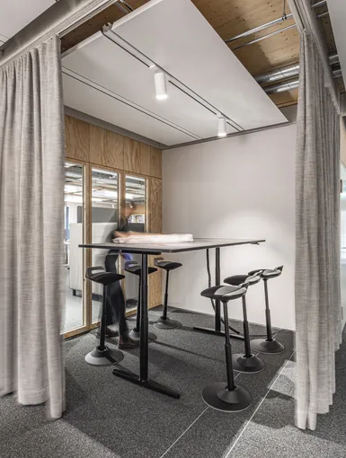 Besprechungszone mit Hochtisch und Barhockern, durch Vorhänge abtrennbar.