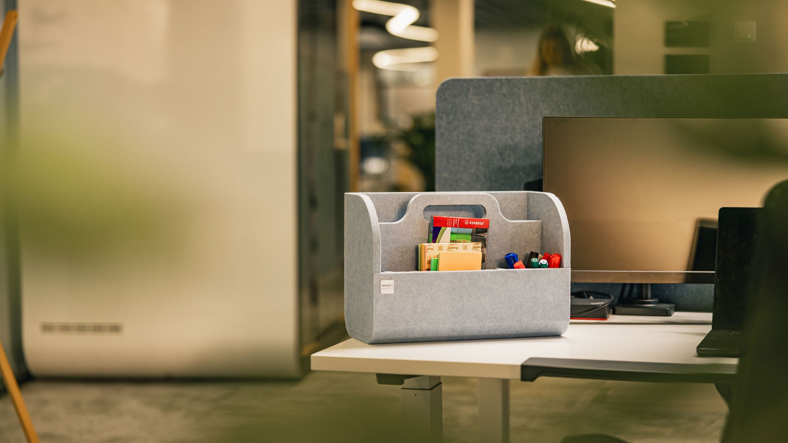 Grauer Büro-Organizer mit Stiften und Notizen auf einem modernen Arbeitsplatz.