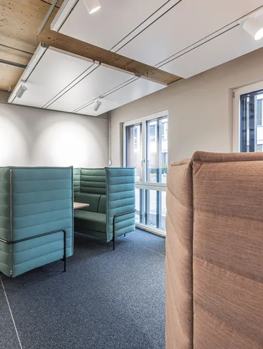 Ruhiger Arbeitsbereich mit hohen gepolsterten Sitzkojen in Pastelltönen.