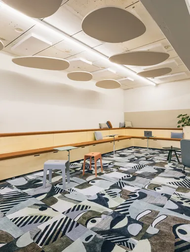 Modernes Open-Space Büro mit hellen Möbeln und kreativem Teppichdesign