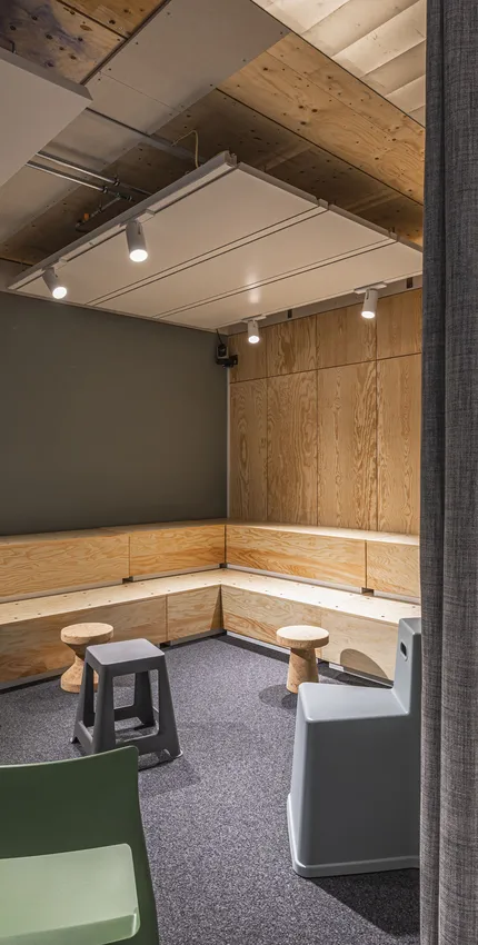 Gemütlicher Raum mit Holzsitzbank, Hockern und gedämmter Beleuchtung.