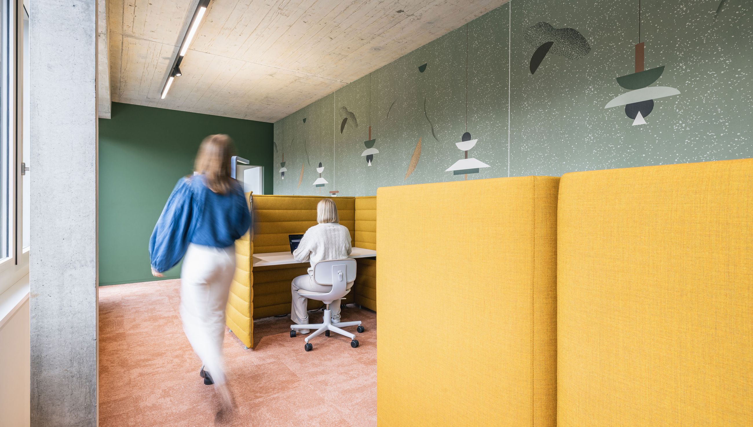 Ruhige Fokuszone mit gelben Akustik-Workpods, grün gestalteter Wand und warmem Teppichboden.