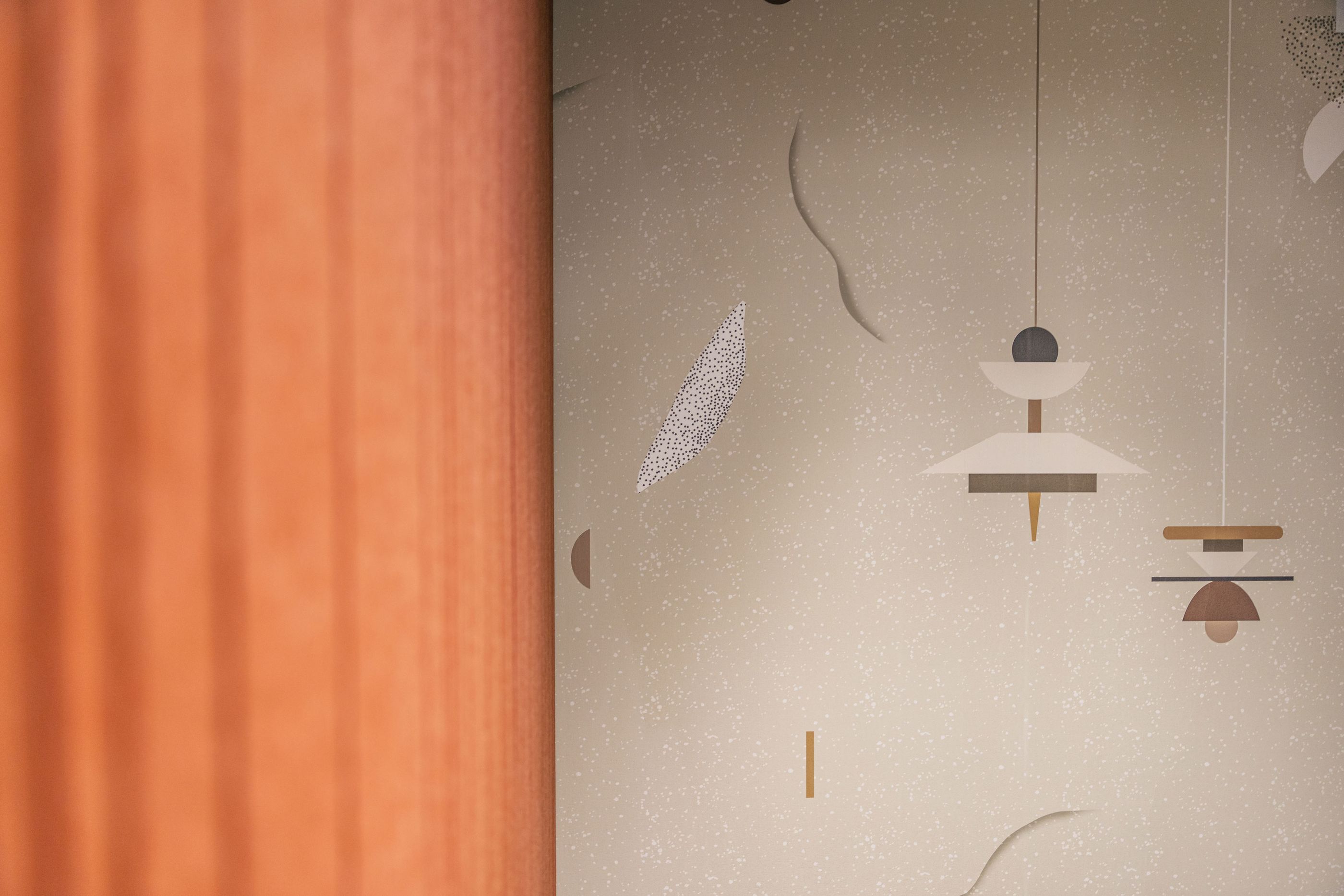 Detailaufnahme einer modernen Bürowand mit abstrakten grafischen Formen und warmen Farbtönen.