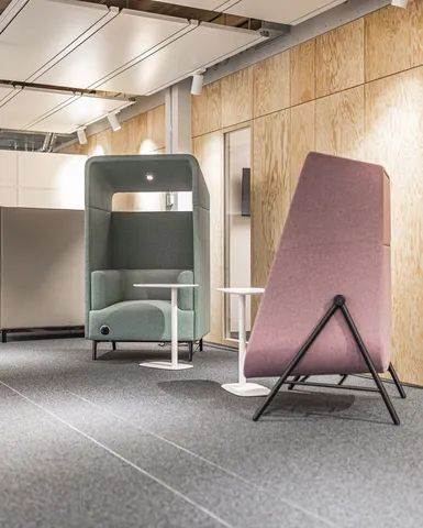 Ruhiger Rückzugsraum mit Sessel und Hocker vor Holzverkleidung.