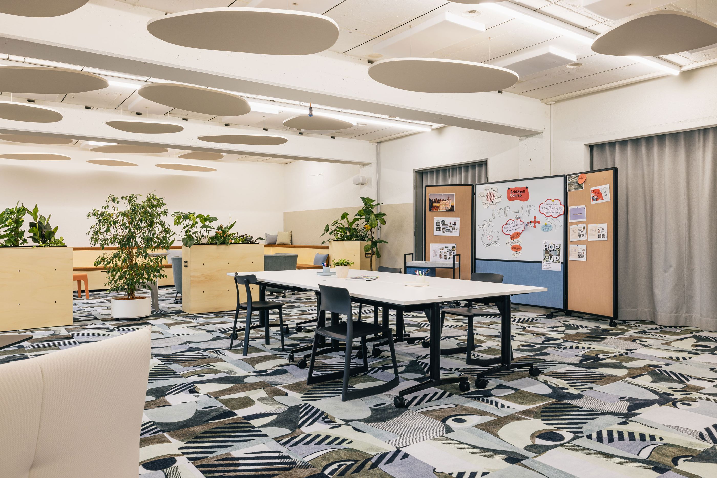 Meetingraum mit weißem Tisch und grauen Stühlen