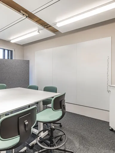 Besprechungszone mit Hochtisch und Barhockern, durch Vorhänge abtrennbar.