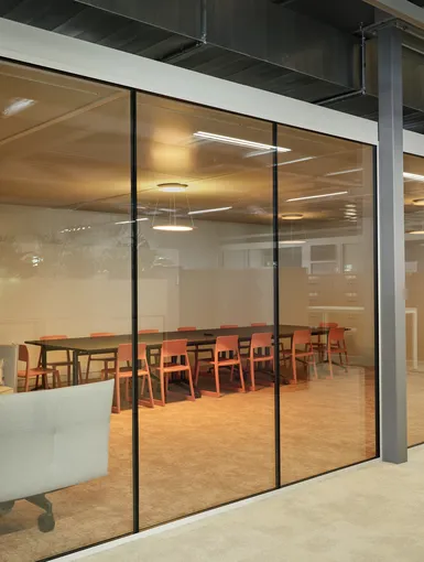Glasscheibe zum Workshopraum mit bunten Stühlen.