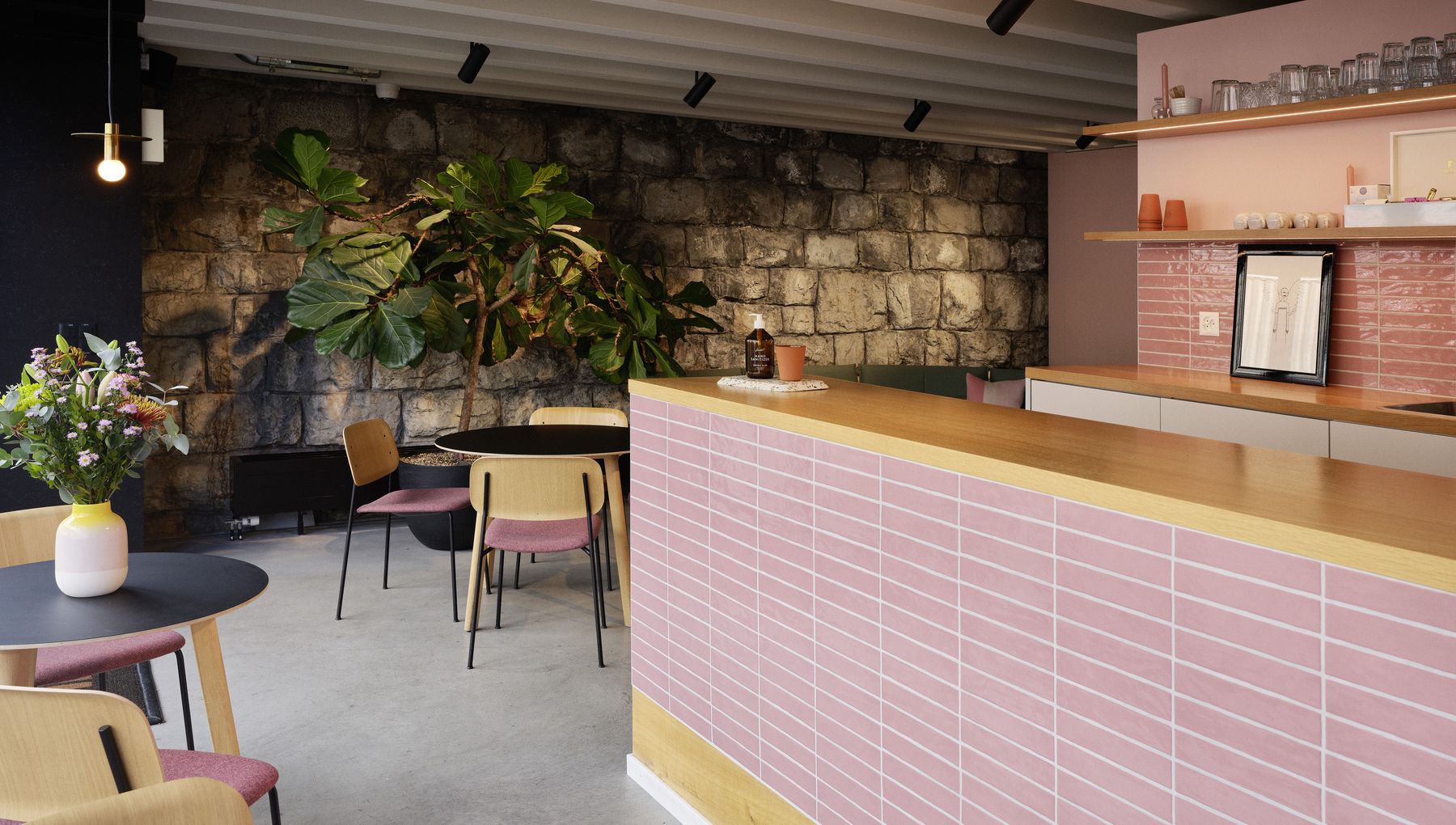 Heller Office-Community-Bereich mit Designsofa, Pflanzenregal und moderner Büroküche.