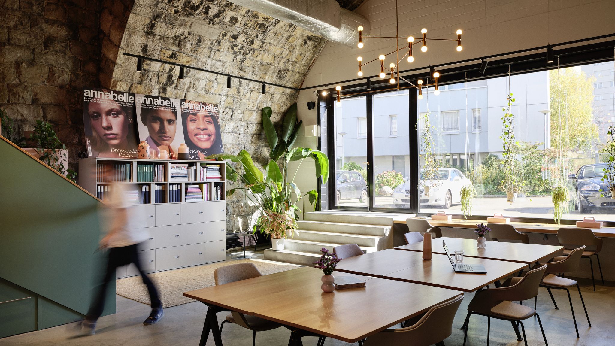 Moderner Besprechungsbereich mit hellem Holztisch und minimalistischem Hocker in warmem Office-Design.