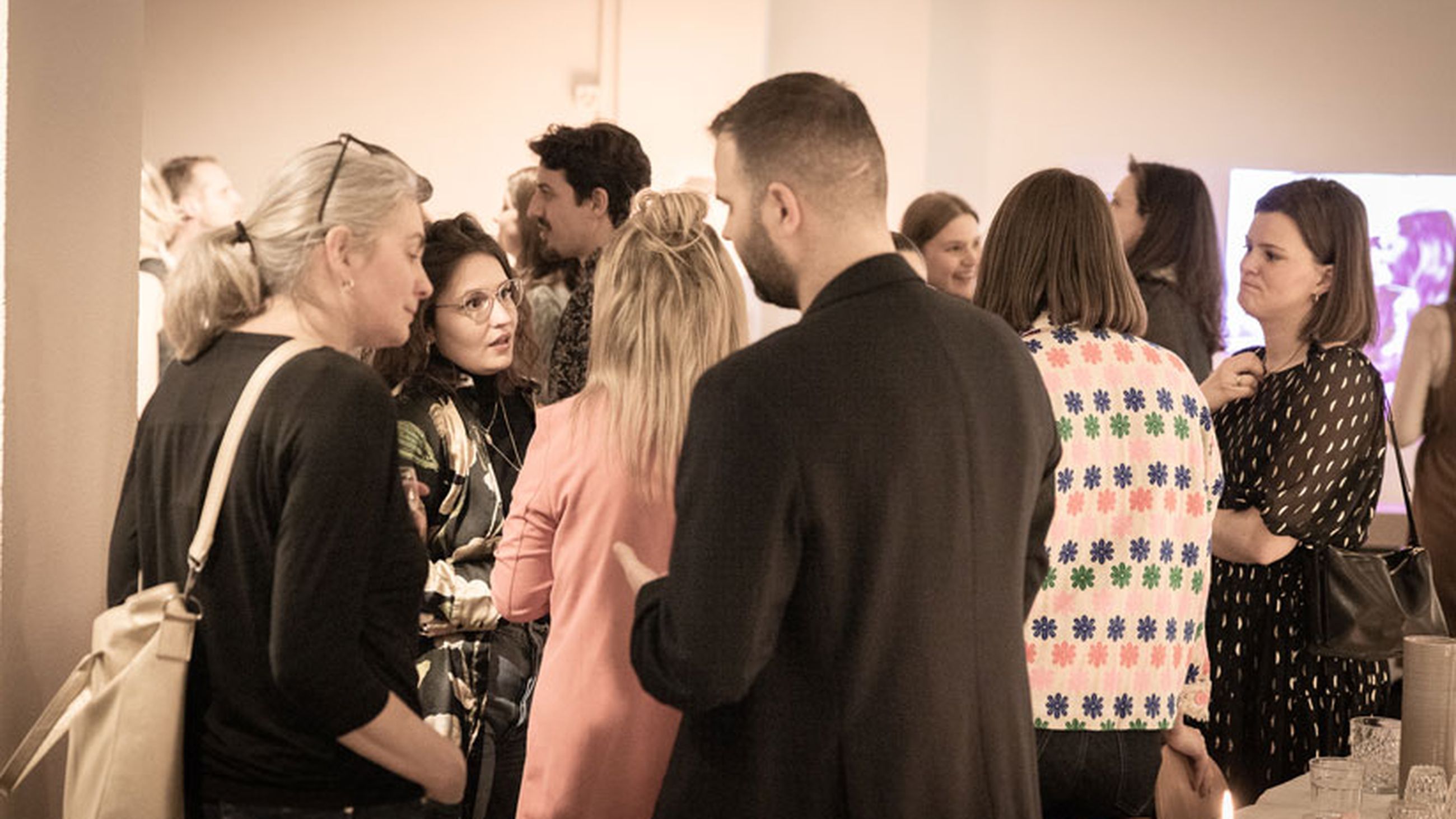 Personengruppe in angeregter Unterhaltung, im Hintergrund weitere Personen.