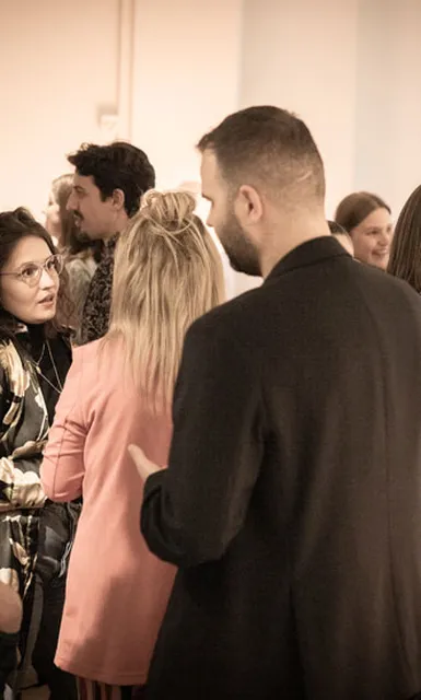 Personengruppe in angeregter Unterhaltung, im Hintergrund weitere Personen.