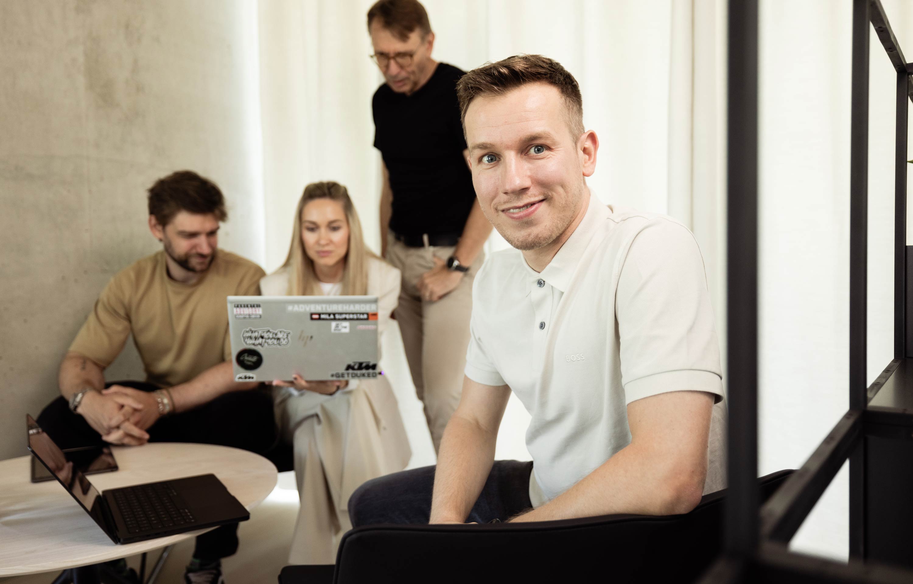 Handsome young man sitting in the front and behind him the three consultants are discussing a project.
