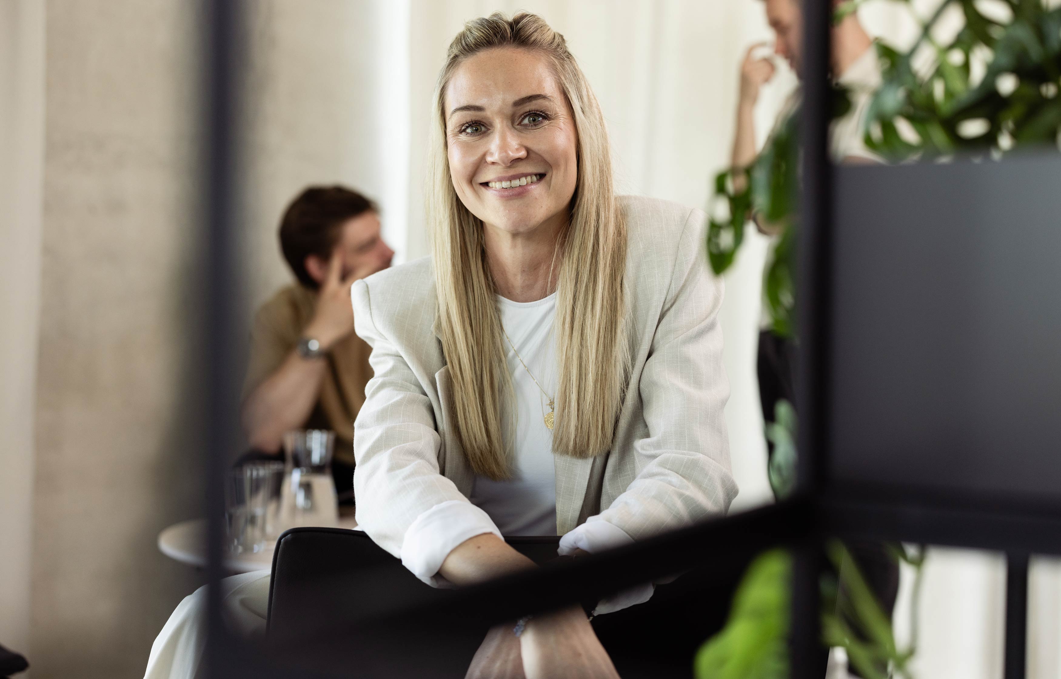 There is a confident woman sitting on a stool looking straight into the camera.