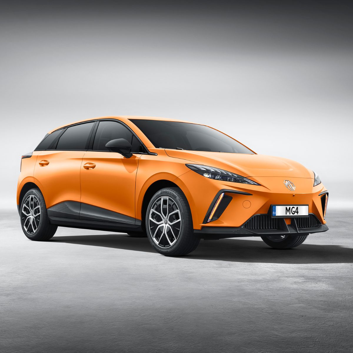 Ein orangefarbener MG4 mit abgedunkelten Scheiben ist geparkt.