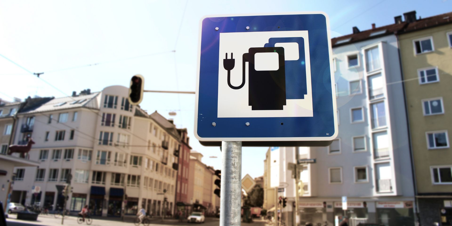 Ein Schild in einer Innenstadt bildet zwei Ladesäulen ab, die den Parkplatz als Ladeplatz für E-Autos kennzeichnen.