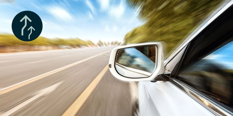 Weißes Auto fährt in hoher Geschwindigkeit über die Autobahn