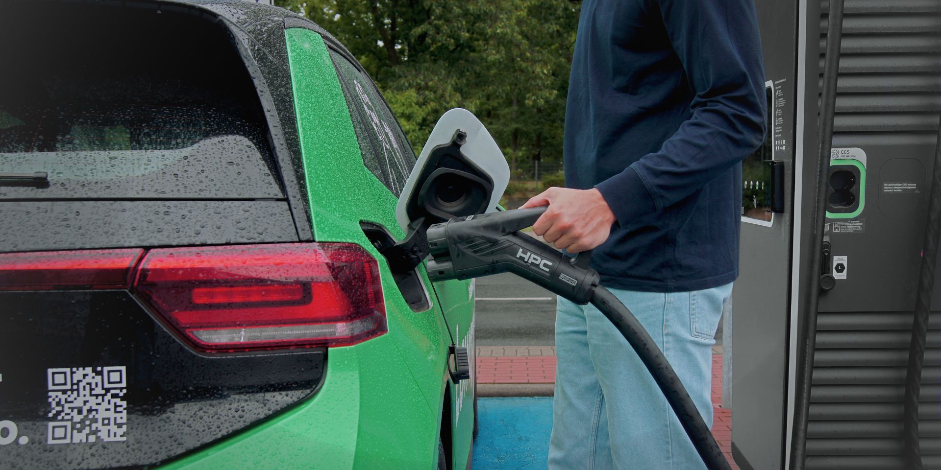 Mann hat einen Ladestecker in der Hand und steckt diesen in ein e-Auto