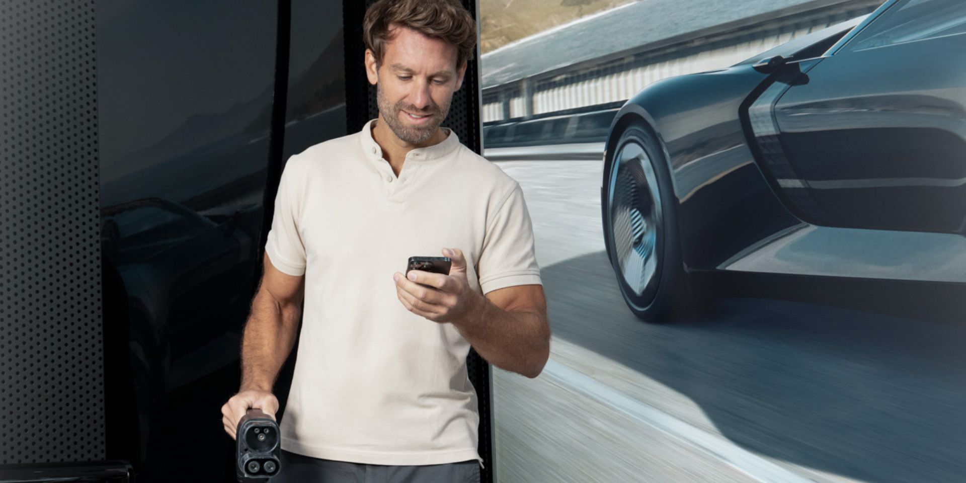 Mann mit Smartphone in der Hand vergleicht Ladetarife.