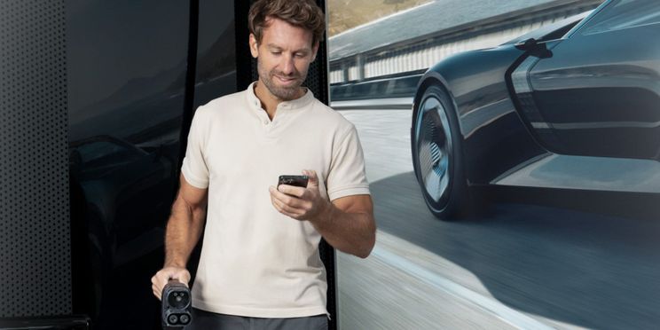 Mann mit Smartphone in der Hand vergleicht Ladetarife.