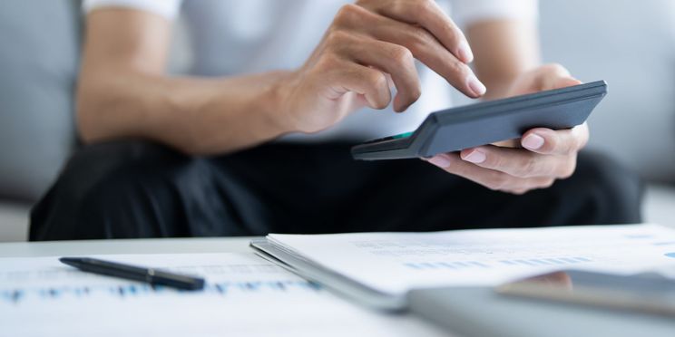 Mann vergleich Ladekosten mit Taschenrechner und Diagrammen.