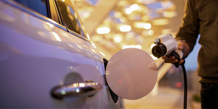 Person hält Stecker des e-Autos in der Hand, um es in die geöffnete Ladeklappe zu stecken.