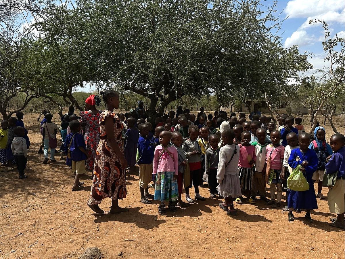 Große Kindergruppe versammelt sich im Schatten der Bäume.