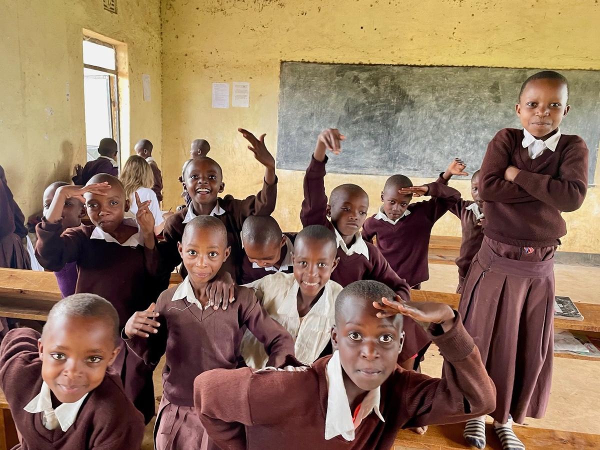 Klassenraum voller Kinder, die in die Kamera winken.
