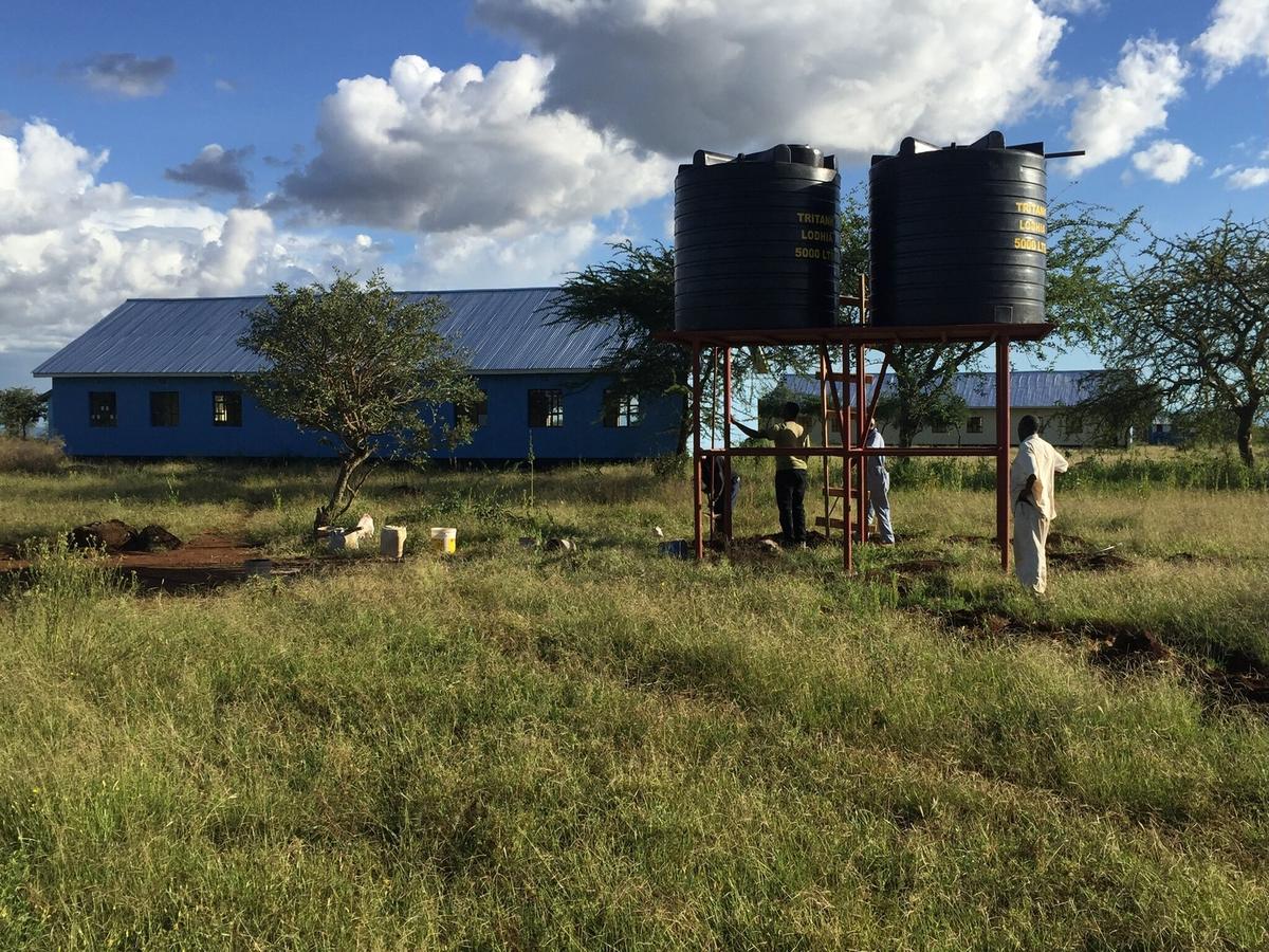 Wassertanks auf dem Stahlgerüst, die Schule dahinter.