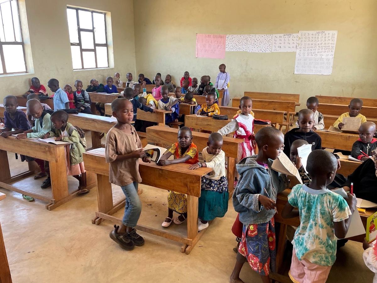 Voller Klassenraum mit Bänken, Kindern und Lehrkraft.