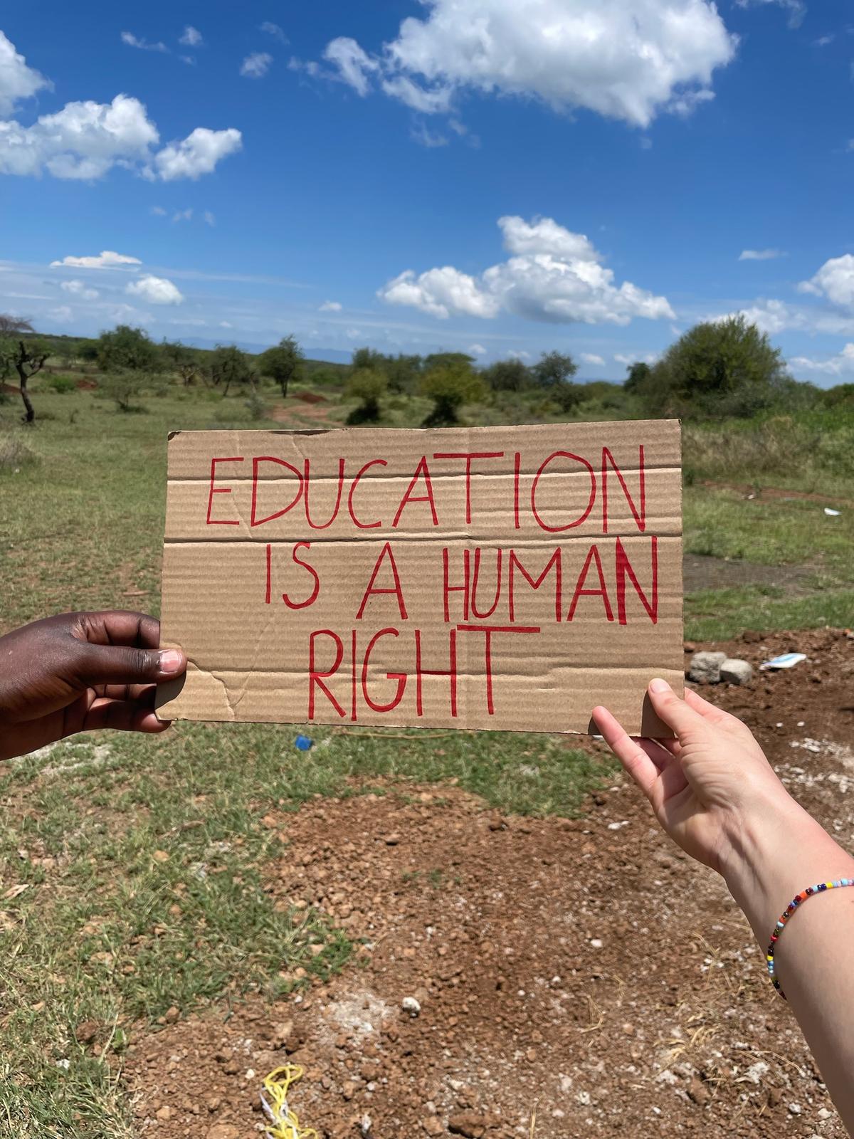 Zwei Hände halten "EDUCATION IS A HUMAN RIGHT" Schild