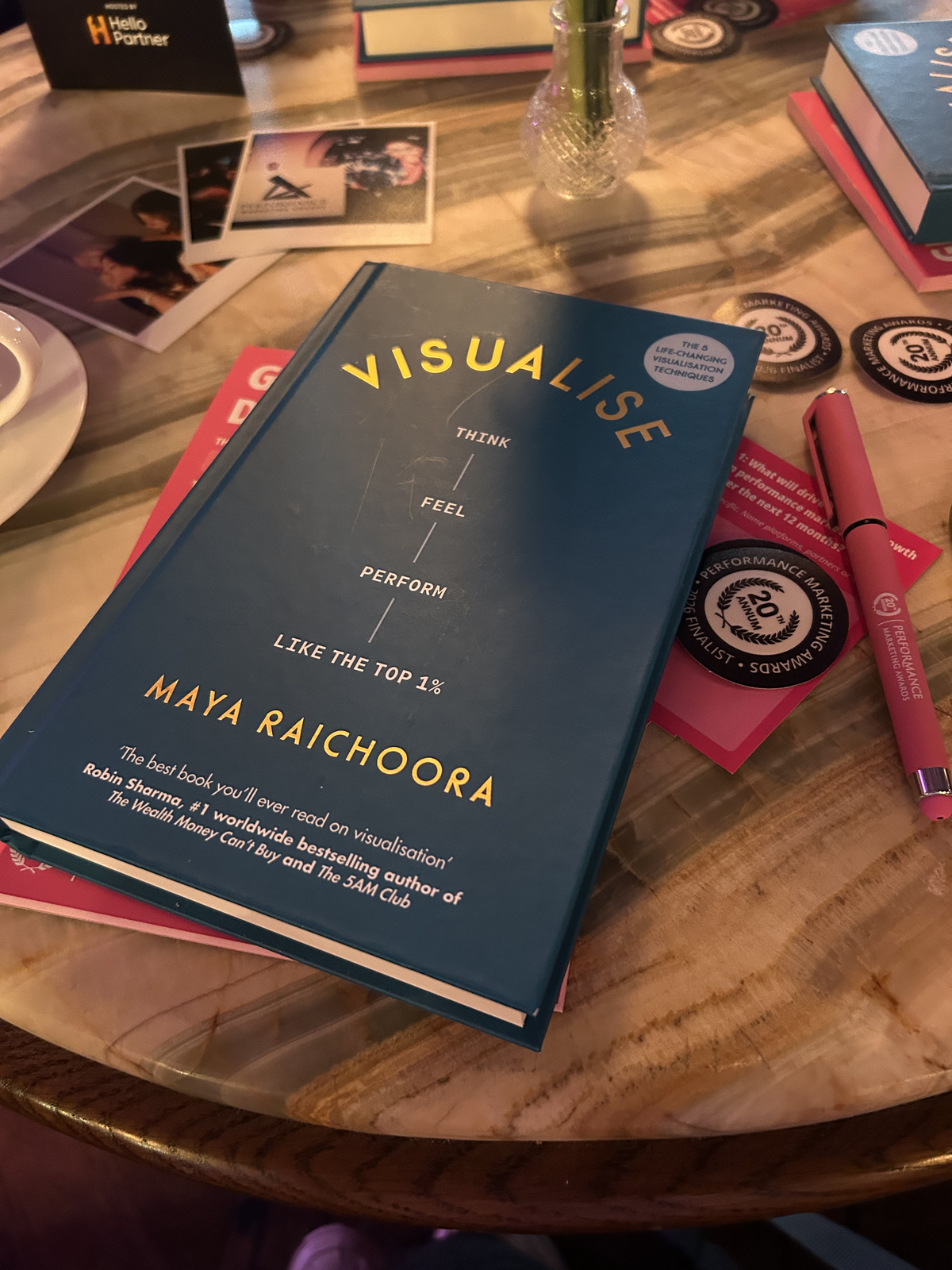 A book on a desk at the PMA Finalists' Brunch, with a pen, polaroids, stickers