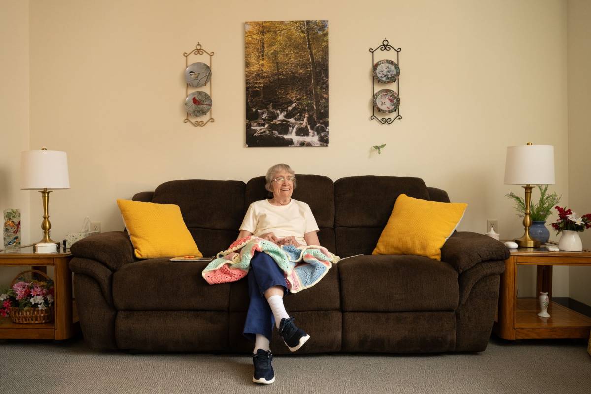 Resident relaxing on a sofa in a warm apartment living room with wall art.