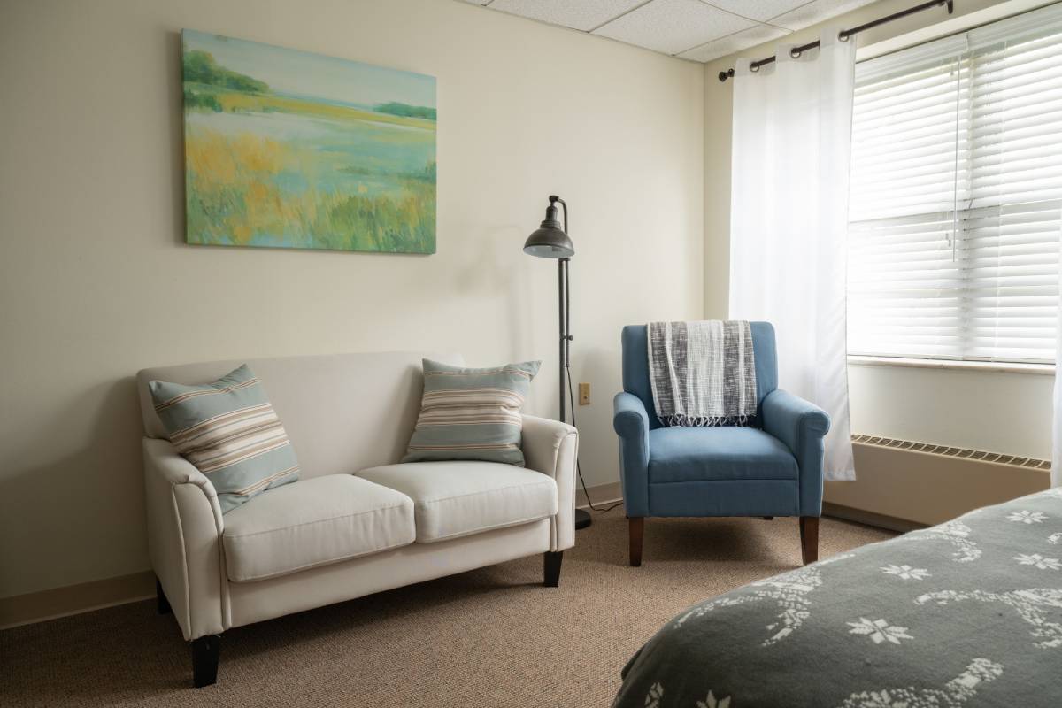 Pitman Manor apartment living area with sofa, blue accent chair and large window.