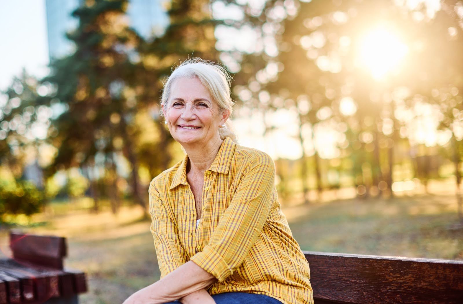 Portrait of an elderly woman outdoors. Happy senior woman sitting on a bench in a park