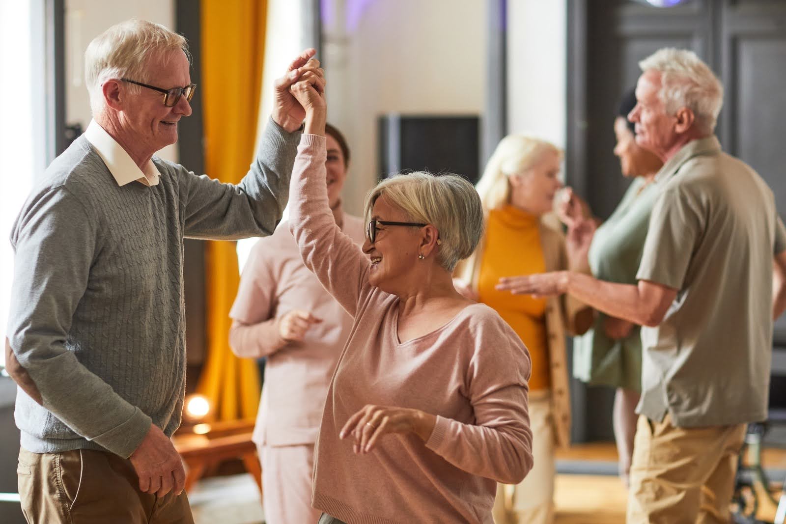 Group of smiling seniors dancing while enjoying activities in retirement home