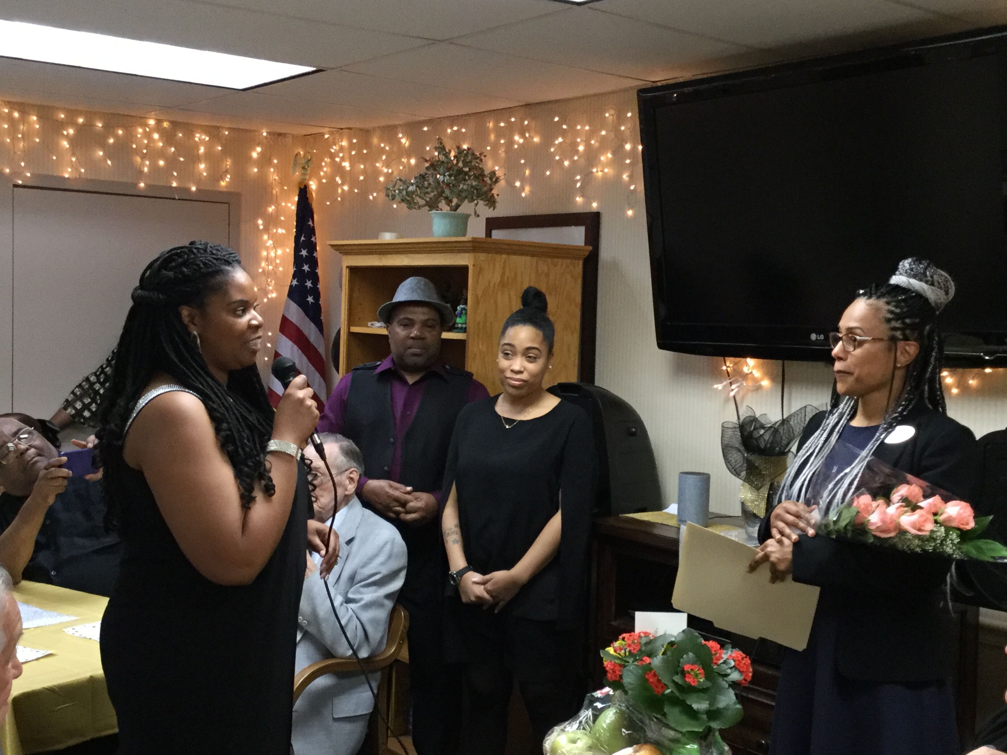 On behalf of all Covenant Place associates, Tamika Green, administrative assistant; Desmond Q. Green, maintenance associate; and Tammie Forbes, social service coordinator, present a bouquet of roses to India Santos, housing administrator.