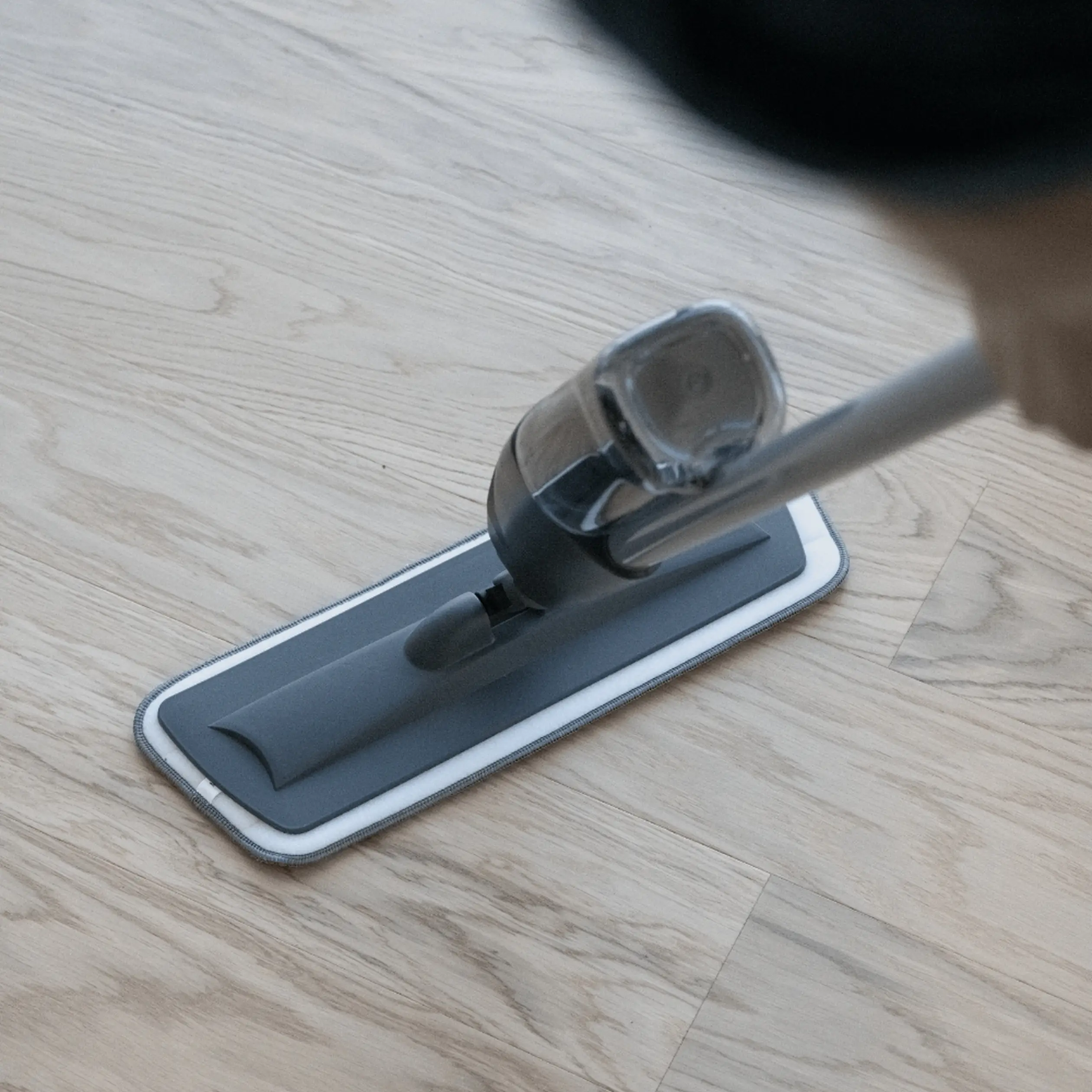 A modern cleaning scene showing a mop gliding over light wood flooring, emphasizing cleanliness and care for natural surfaces.