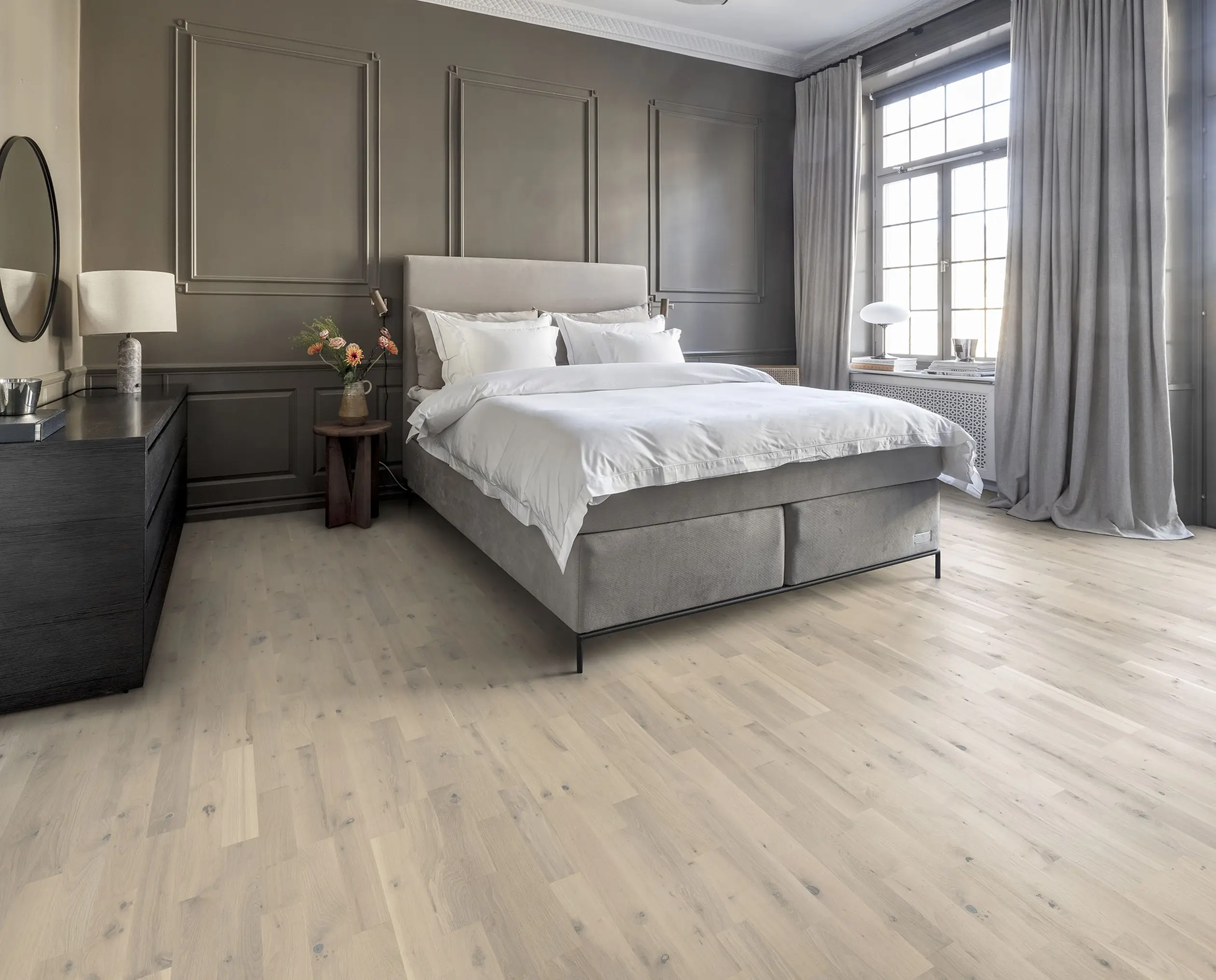 Elegant bedroom with light wood flooring, gray walls, and a cozy upholstered bed.