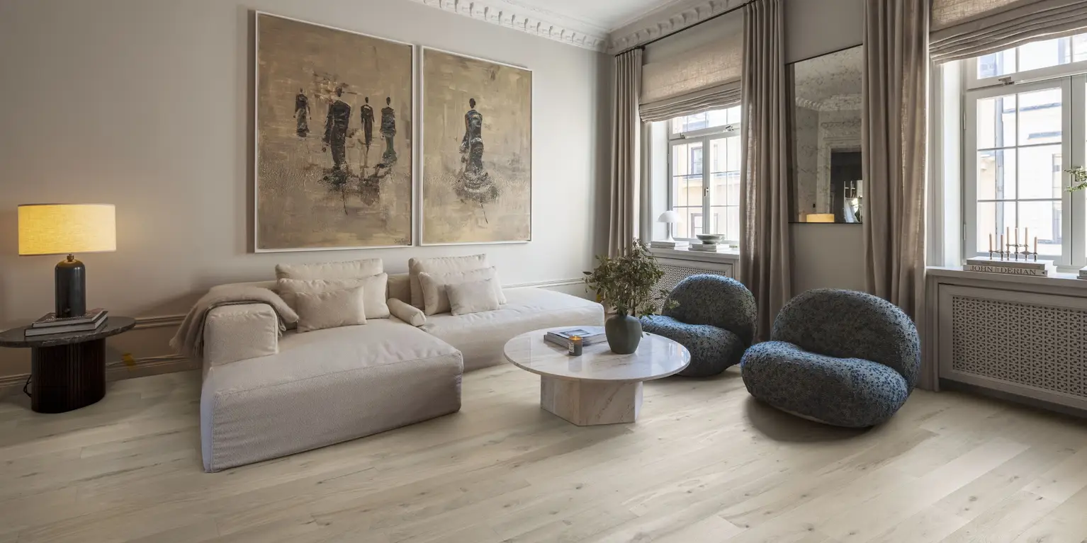 Elegant living room with beige furniture, blue chairs, and light wood flooring.